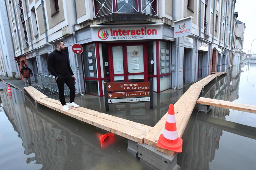 Un homme marche sur des planches dans une rue inondée après que la Vilaine soit sortie de son lit à Redon, le 29 janvier 2025.