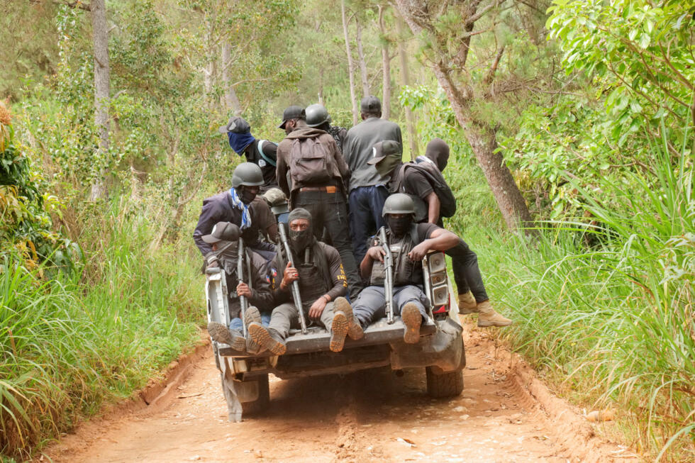 Miembros de un grupo de vigilancia vecinal suben una colina mientras patrullan una zona residencial después de que bandas incendiaran casas, según estimaciones de la ONU, en Furcy, Haití, 24 de junio de 2025.
