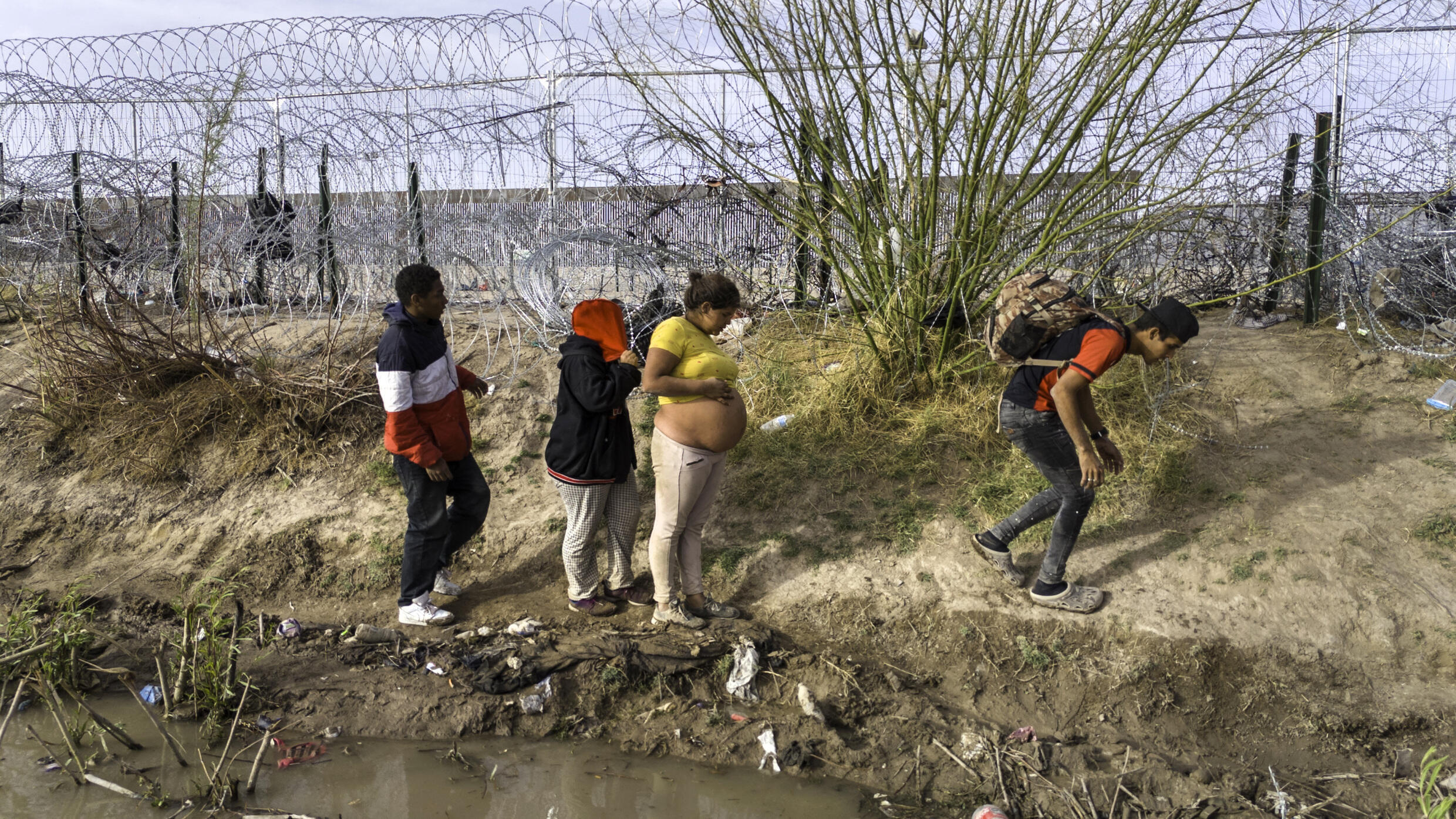 En una vista aérea, una mujer venezolana embarazada camina a lo largo de la orilla del Río Grande después de cruzar la frontera entre Estados Unidos y México el 13 de marzo de 2024 en El Paso, Texas, Estados Unidos