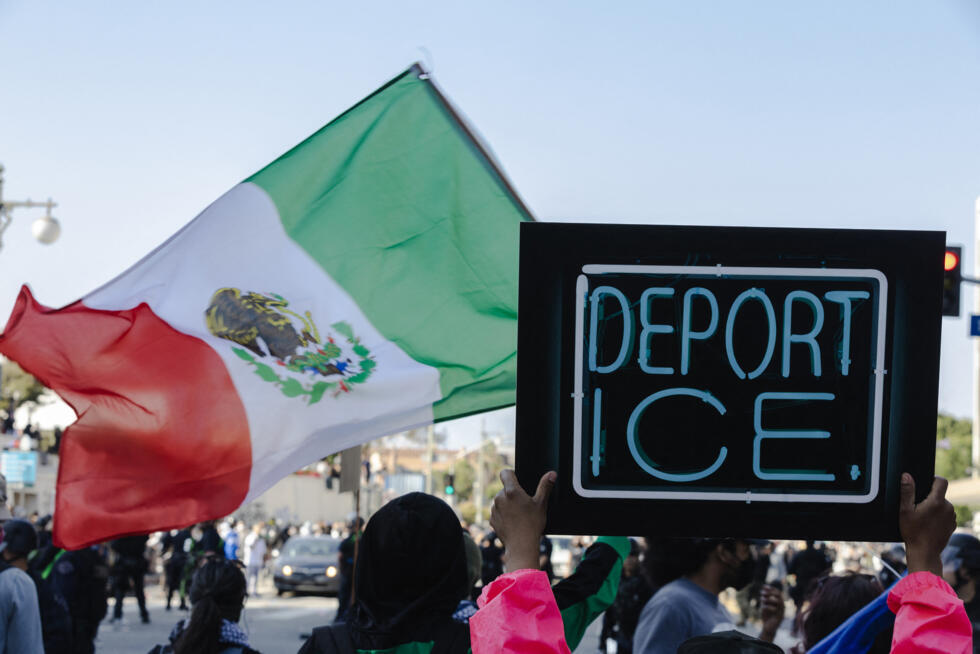 Manifestantes sostienen pancartas contra el ICE y una bandera mexicana durante los enfrentamientos entre la policía y los manifestantes el 8 de junio de 2025 en el centro de Los Ángeles, California. Los enfrentamientos se producen después de las redadas del ICE en la ciudad durante el fin de semana.