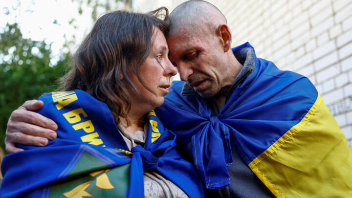 Oleksandr, prisonnier de guerre ukrainien, embrasse sa femme qu'il a retrouvée après un échange de prisonniers avec l'armée russe, dans un lieu non révélé en Ukraine, le 23 mai 2025.