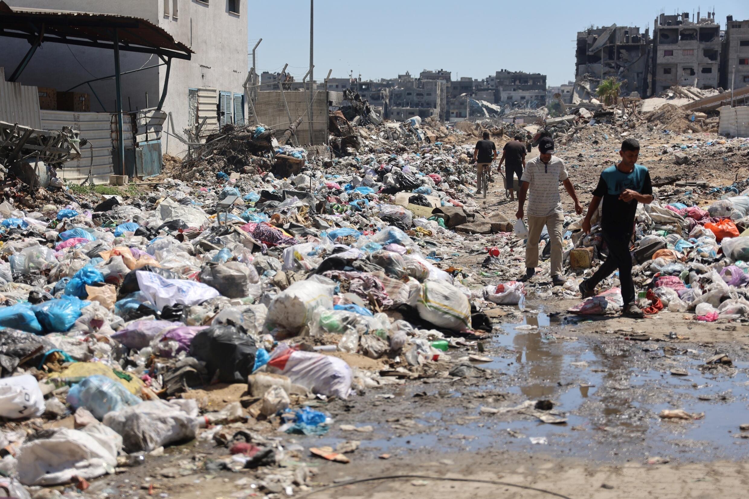 Des Palestiniens passent devant des monticules d'ordures et des égouts dans le quartier de Cheikh Radwane, au nord de la ville de Gaza, le 3 juillet 2024
