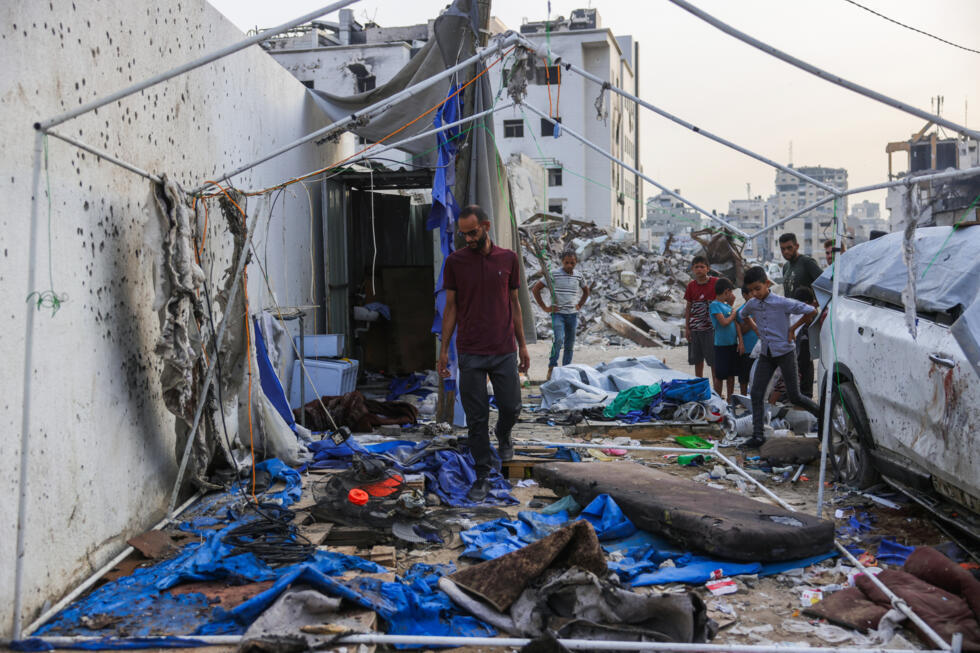 Des personnes regardent les restes de la tente utilisée par les journalistes d'Al Jazeera à Gaza-ville, devant l'hôpital al-Chifa, après une frappe israélienne, le 11 août 2025.