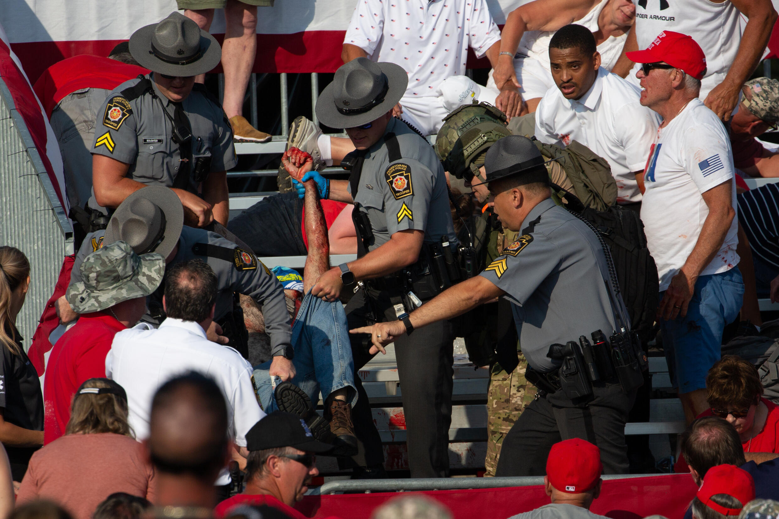 Une personne est évacuée des tribunes par des policiers après que des coups de feu ont été tirés sur l'ancien président Donald Trump lors d'un meeting de campagne à Butler, le 13 juillet 2024 en Penns