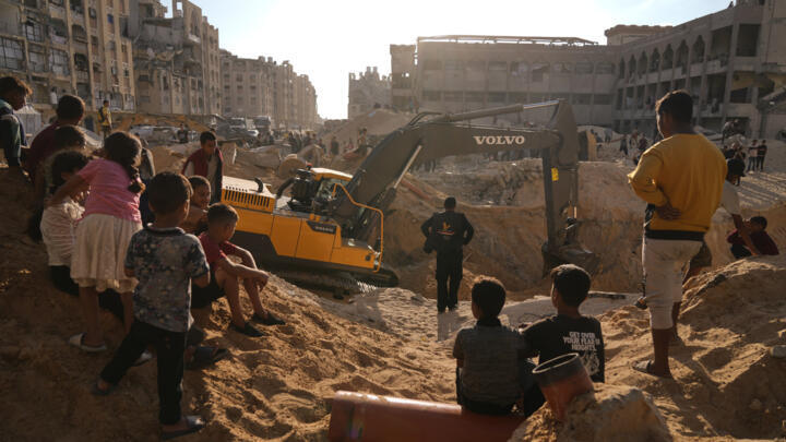 Palestinians watch machinery and some workers from Egypt searching for the bodies of hostages at Hamad City, in Khan Younis, southern Gaza Strip, Sunday, October 26, 2025.