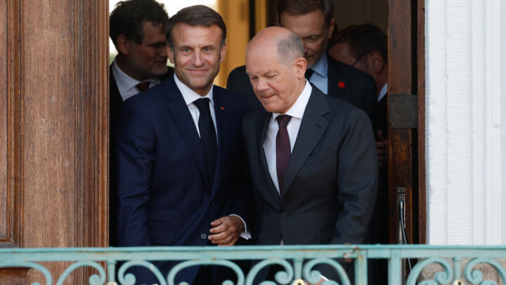 French President Emmanuel Macron, left, and German Chancellor Olaf Scholz arrive with fellow ministers for a family photo at the end of a joint Franco-German cabinet meeting of ministers in front of S