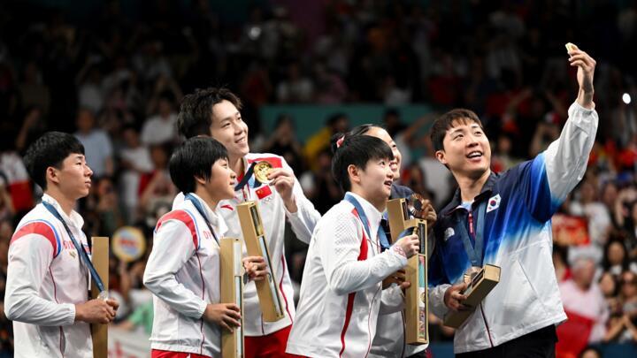 South Korea's Lim Jonghoon takes a selfie with his teammate and Chinese and North Korean mixed table tennis team medallists