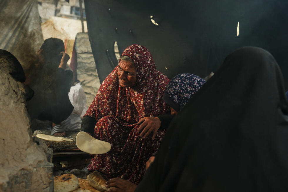Mujeres palestinas hornean pan en un horno de barro, utilizando plástico como combustible, en una escuela de la ONU utilizada como refugio para palestinos desplazados en Khan Younis, el domingo 5 de octubre de 2025.