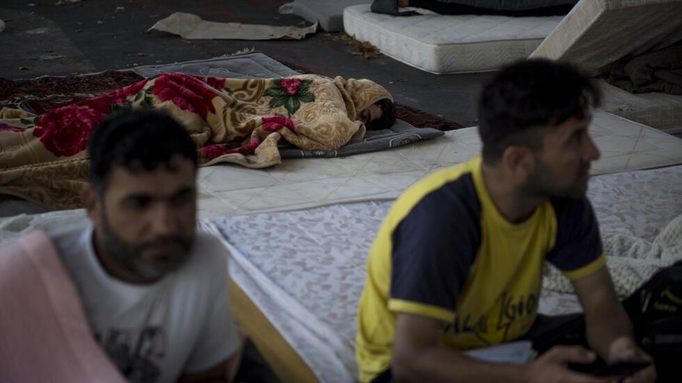 A man sleeps among mattresses on the ground in the migrant camp in the Stalingrad district of Paris on July 12, 2023. (Photo by JULIEN DE ROSA / AFP)