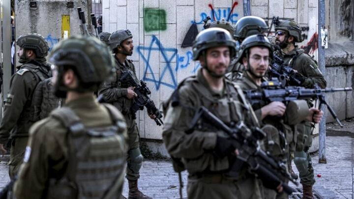 Israeli army soldiers stand guard as Israeli Jewish settlers tour the old market in the city of Hebron in the occupied West Bank on December 28, 2024.
