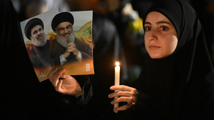 A mourner holds pictures of slain Hezbollah leader Hassan Nasrallah during a ceremony marking his first death anniversary in Beirut's southern suburbs on September 26, 2025.