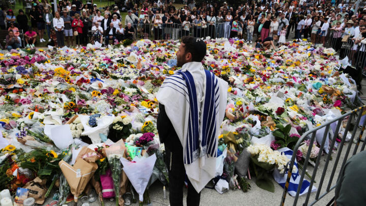 Rabbi Yossi Friedman speaks to people gathering at a flower memorial by the Bondi Pavilion at Bondi Beach on December 16, 2025, following Sunday's shooting in Sydney, Australia.