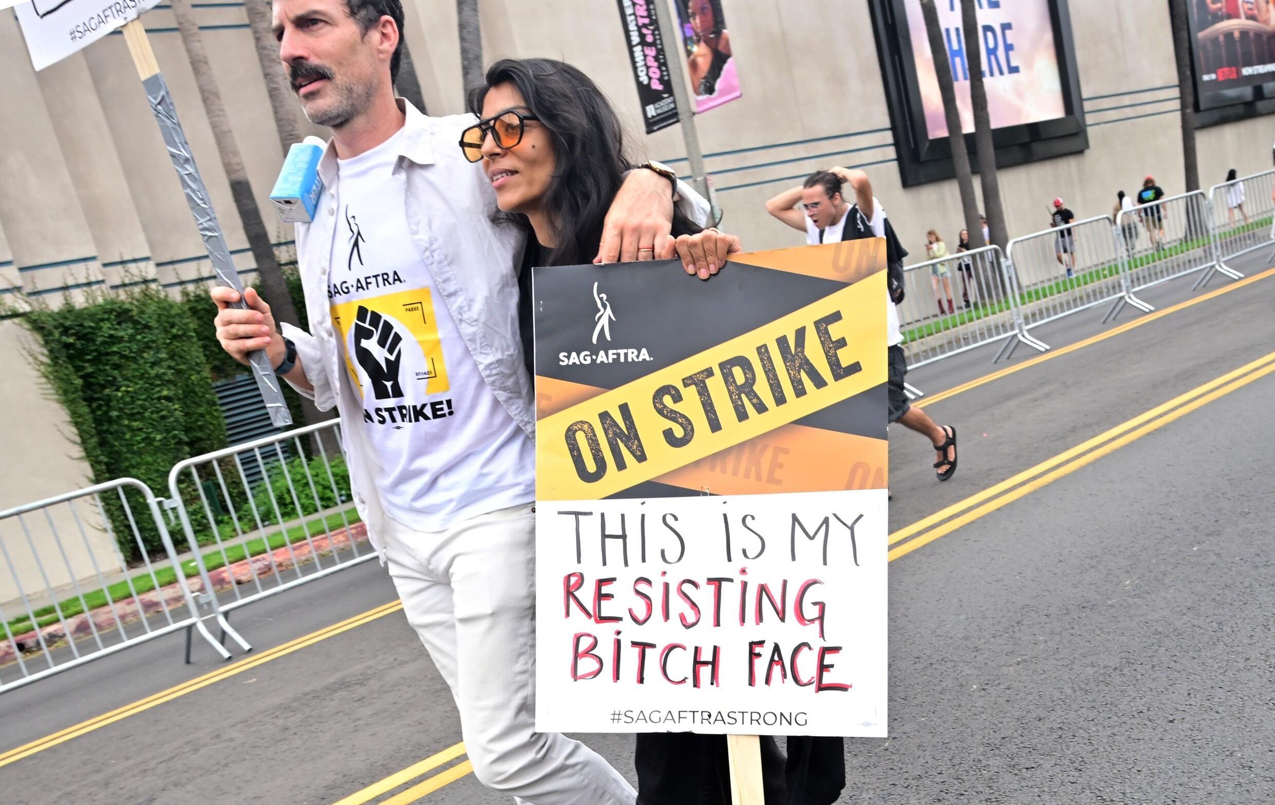 Dos manifestantes portan carteles durante una marcha en solidaridad con los guionistas y actores de Hollywood en huelga, el 13 de septiembre de 2023 en Los Ángeles