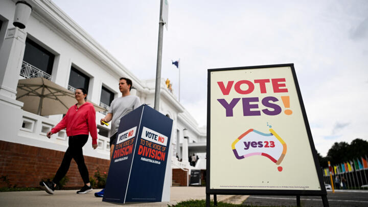 Voters walk past Vote 'Yes' and Vote 'No' signs at the Old Australian Parliament House in Canberra on October 14, 2023.