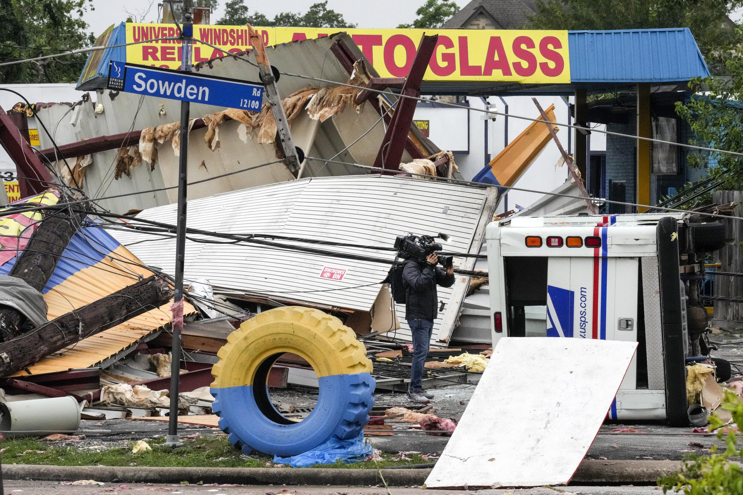 Un reportero gráfico filma los daños en una tienda de neumáticos en la intersección de Sowden y Bingle tras una fuerte tormenta el viernes 17 de mayo de 2024, en Houston.  La destrucción generalizada paralizó gran parte de Houston mientras los equipos se apresuraban a restablecer el suministro eléctrico y retirar los árboles arrancados y los escombros.