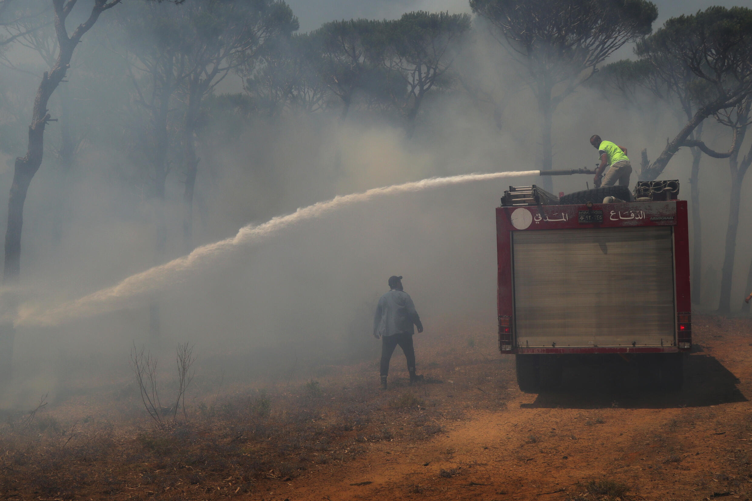 Des secouristes et des pompiers libanais éteignent un incendie provoqué par une frappe israélienne dans une forêt de la ville de Marjayoun, dans le sud du Liban, le 13 juin 2024