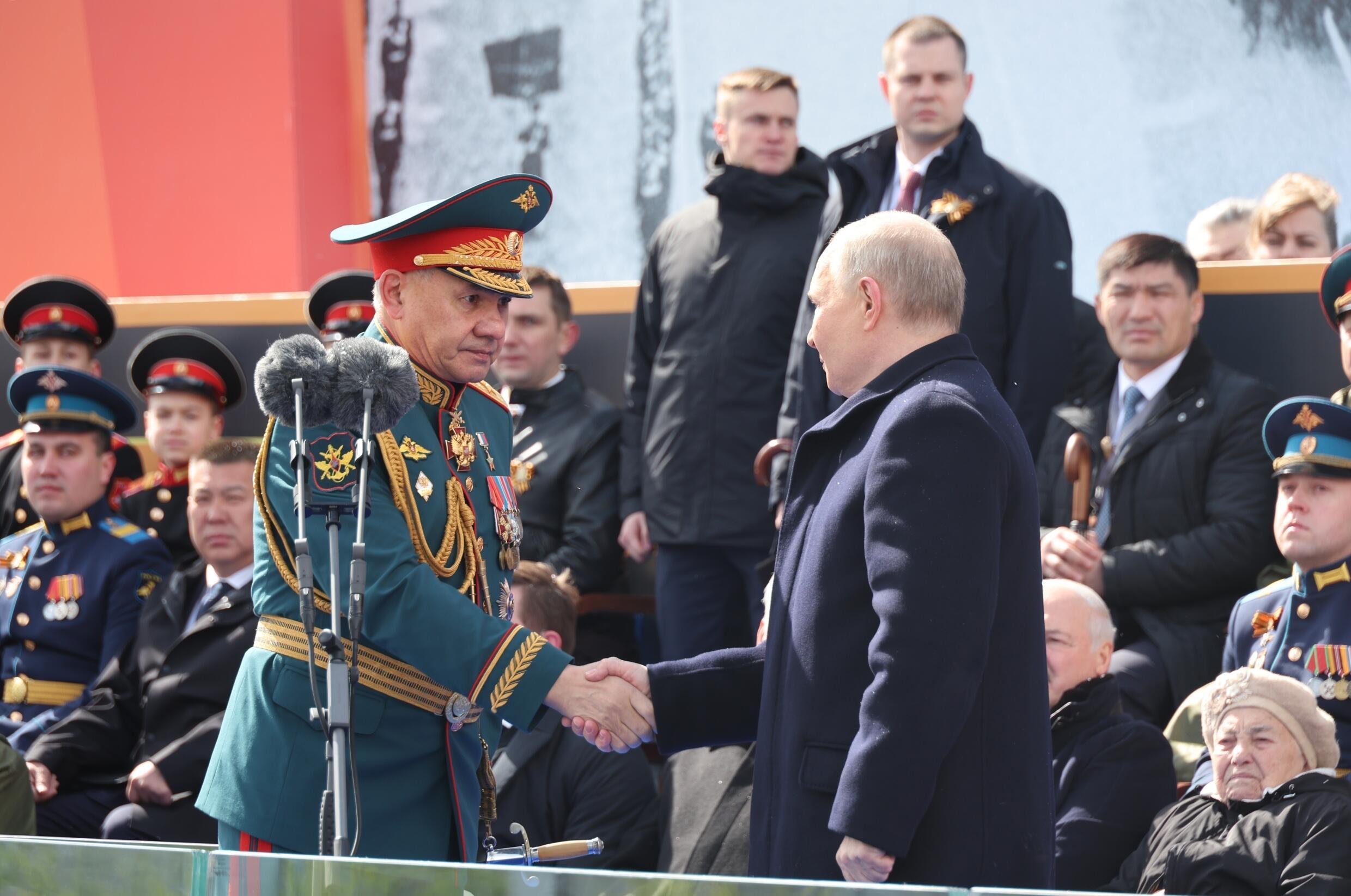 Le président russe Vladimir Poutine (d) serre la main du ministre de la Défense Sergueï Choïgou lors du défilé militaire du Jour de la Victoire sur l'Allemagne nazie, le 9 mai 2024 à Moscou
