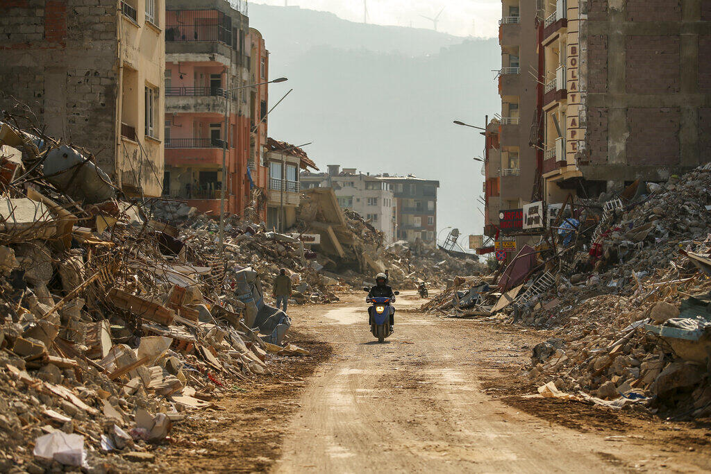 Official figures date the damaged buildings to hundreds of thousands. In this photo, a man rides a motorcycle through the rubble of destroyed buildings in Samandag, southern Turkey, Wednesday, February 22, 2023.