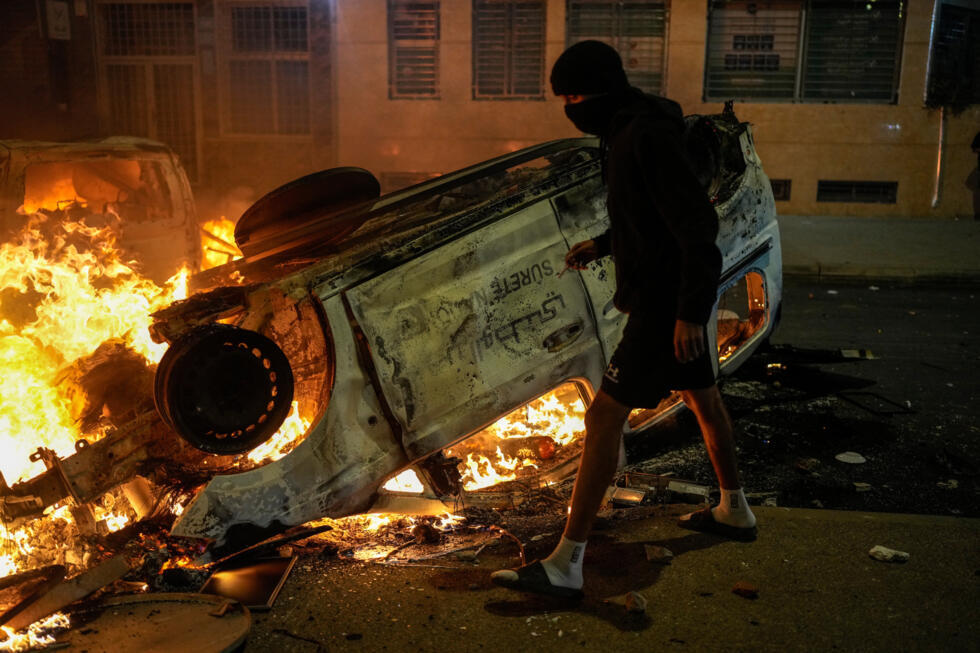 Un jovén junto a un vehículo policial incendiado durante las protestas juveniles en Salé, Marruecos, el 1 de octubre de 2025.