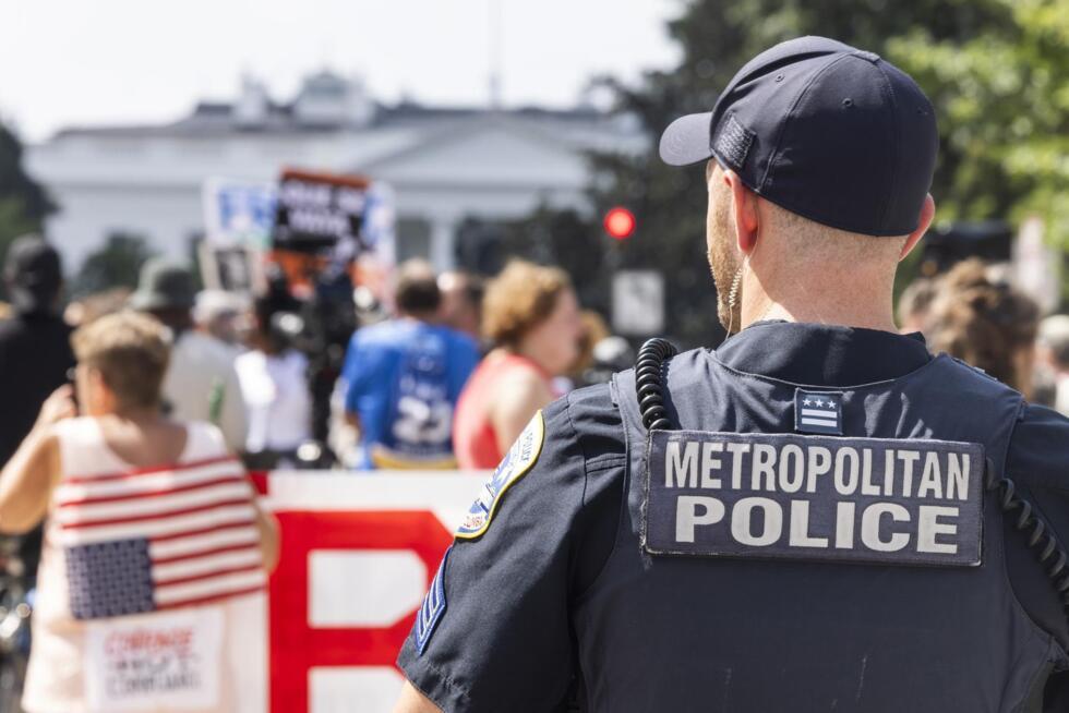 Un agente de policía de Washington D. C. observa a la gente protestar contra la decisión del presidente estadounidense Donald Trump de federalizar la policía de Washington D. C. y desplegar 800 miembros de la Guardia Nacional, en Washington D. C., EE. UU., el 11 de agosto de 2025. Durante una conferencia de prensa en la Casa Blanca, el presidente Trump afirmó que la delincuencia en Washington D. C. está "fuera de control", a pesar de que la violencia en el Distrito se encuentra en su nivel más bajo en 30 años.