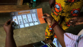 An electoral worker holds a ballot during the presidential election at a polling station in Abidjan on October 25, 2025.