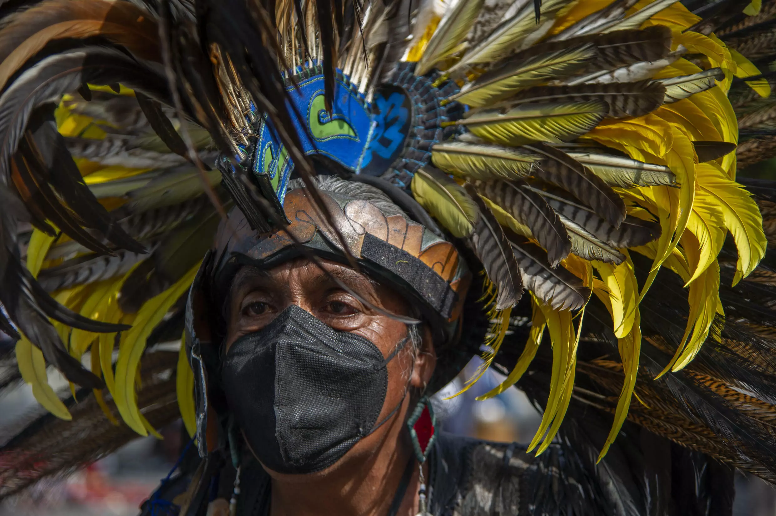 A man wearing a feather headdress prepares to perform an Aztec dance in Mexico City