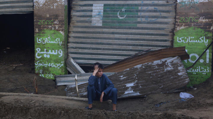 A boy sits in front of shops damaged by Friday's flash flooding on the outskirts of Pir Baba, Buner district, in Pakistan's northwest, Saturday, Aug. 16, 2025.