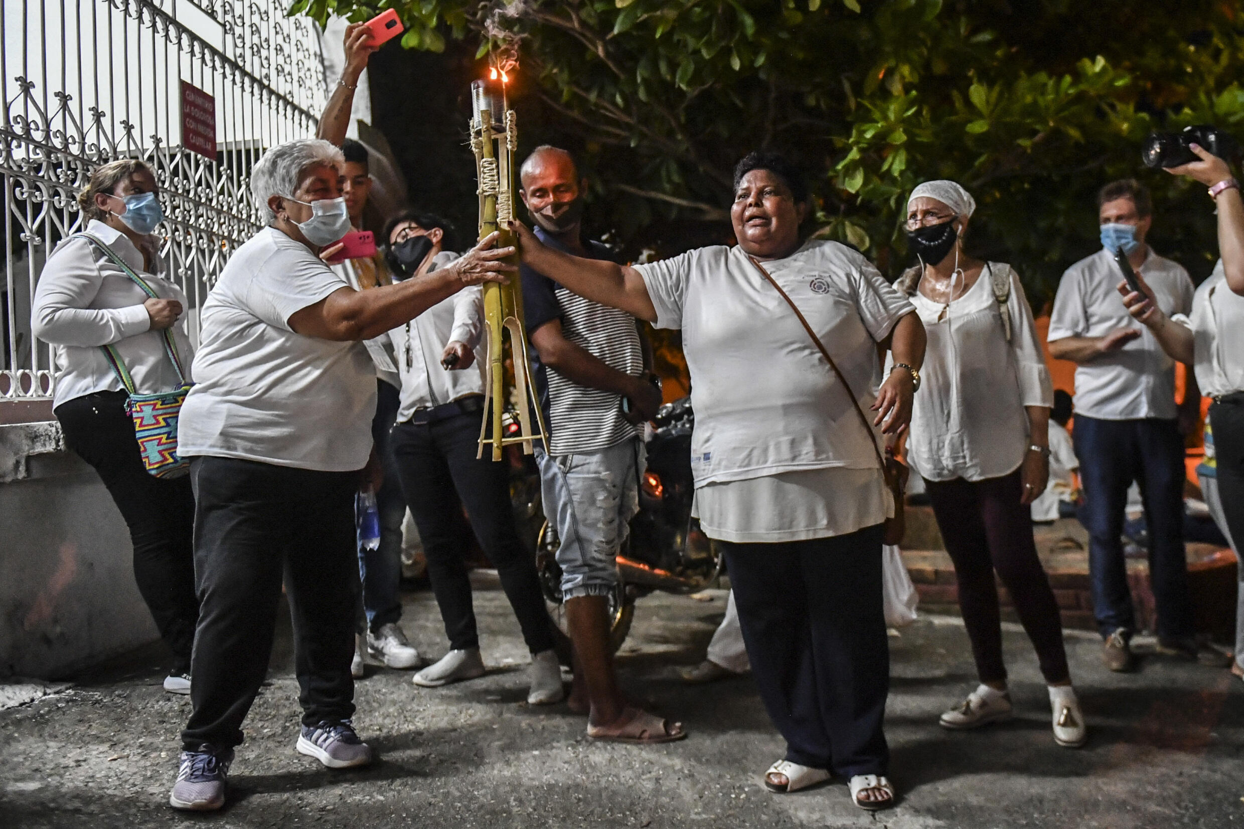 Blanca Bustamante (C), familiar de una víctima de desaparición forzada sostiene una antorcha durante un ritual simbólico en el marco de las audiencias de la Jurisdicción Especial para la Paz (JEP) para evaluar los avances de la investigación de la Unidad de Búsqueda de Personas Desaparecidas en el cementerio de la Dolorosa en Puerto Berrio.