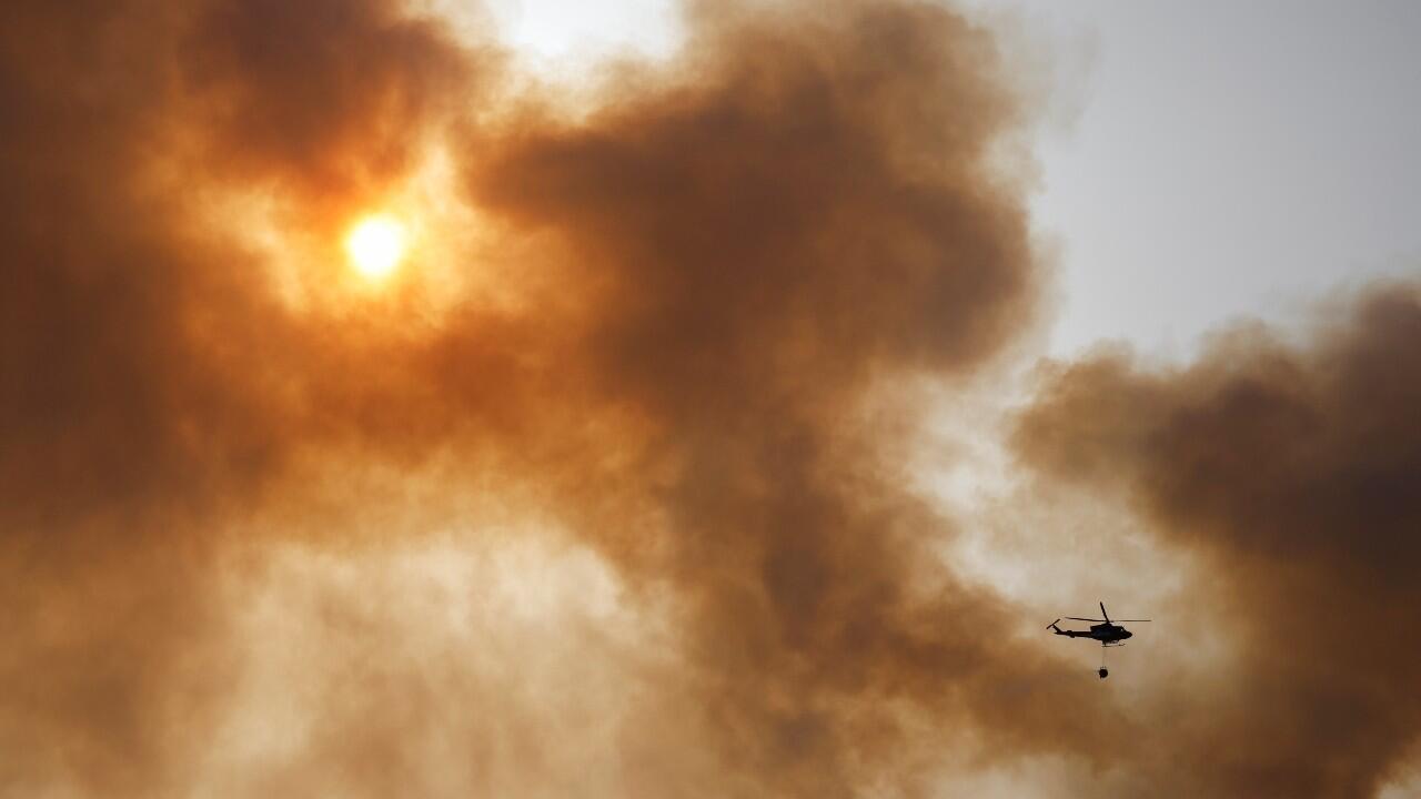 Un helicóptero que transporta agua sobrevuela por humo que se eleva cerca del lugar de un incendio forestal, en la Sierra de Leyre, Yesa, España, el 15 de junio de 2022.