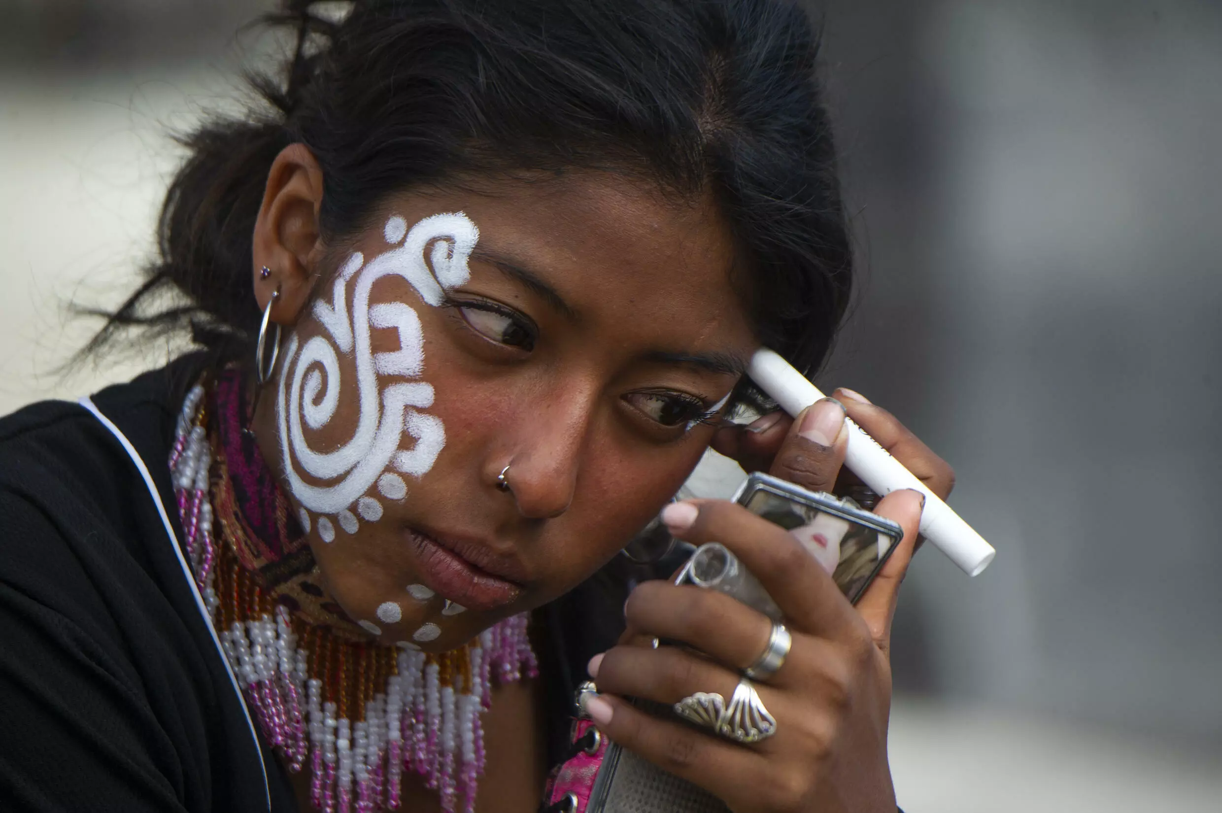 A woman puts on face paint before performing an Aztec dance in Mexico City