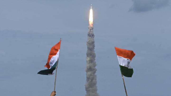 People wave Indian flags as an Indian Space Research Organisation (ISRO) rocket carrying the Chandrayaan-3 spacecraft lifts off from the Satish Dhawan Space Centre in Sriharikota, an island off the coast of southern Andhra Pradesh state on July 14, 2023.
