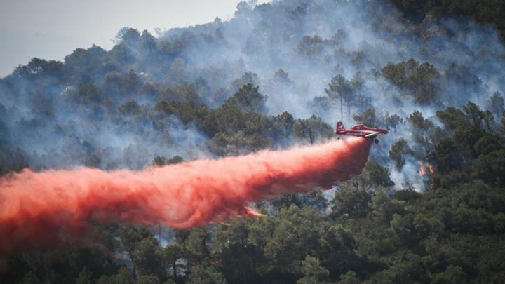 A fire-fighting aircraft Air Tractor AT-802 drops fire retardant over a wildfire near Aussieres neighbourhood, close to the city of Narbonne, southwestern France, on July 8, 2025.
