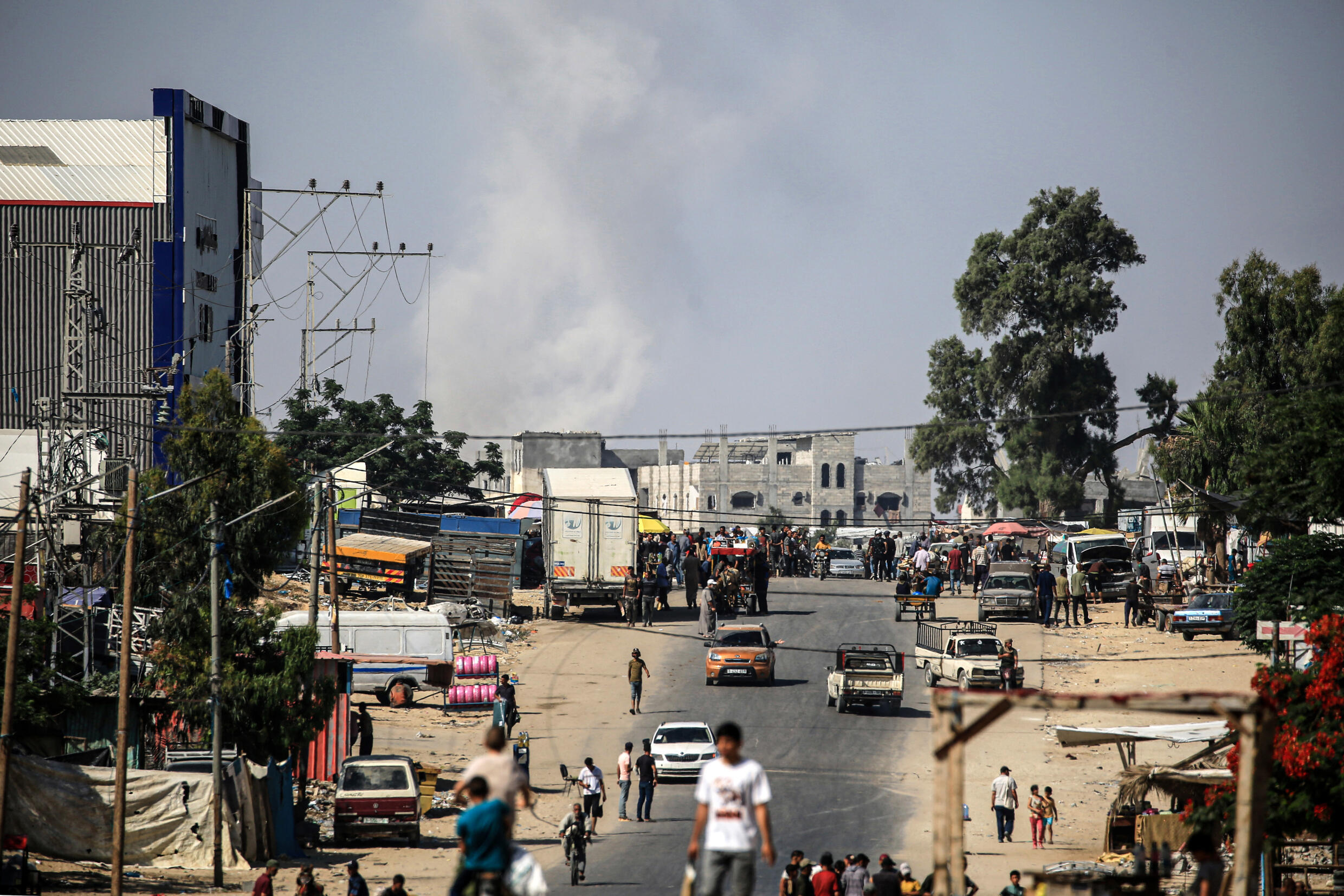 Les Palestiniens poursuivent leurs tâches quotidiennes, alors que la fumée s'élève après le bombardement israélien de la ville de Rafah, dans le sud de la bande de Gaza, le 11 juin 2024.