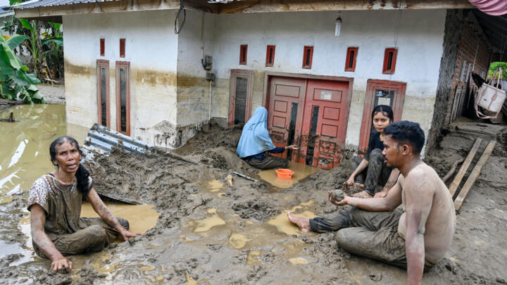 Dozens of people were killed in Indonesia's Aceh province, where residents cleared mud from flooded homes