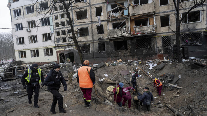 People search for fragments of a rocket inside a crater in a residential neighbourhood in Kyiv,