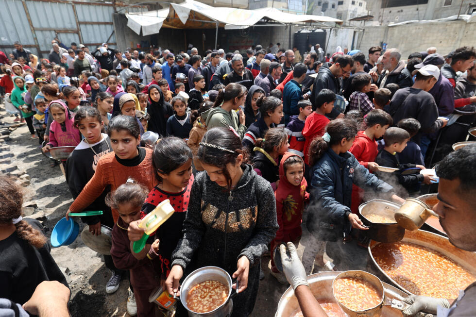 Des Palestiniens lors d'une distribution gratuite de nourriture dans le camp de réfugiés de Nuseirat, dans le centre de la bande de Gaza, le 12 avril 2025.