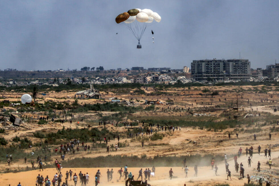 Des Palestiniens se précipitent pour récupérer de l'aide humanitaire parachutée au-dessus de Nousseirat, dans le centre de la bande de Gaza, le 5 août 2025.