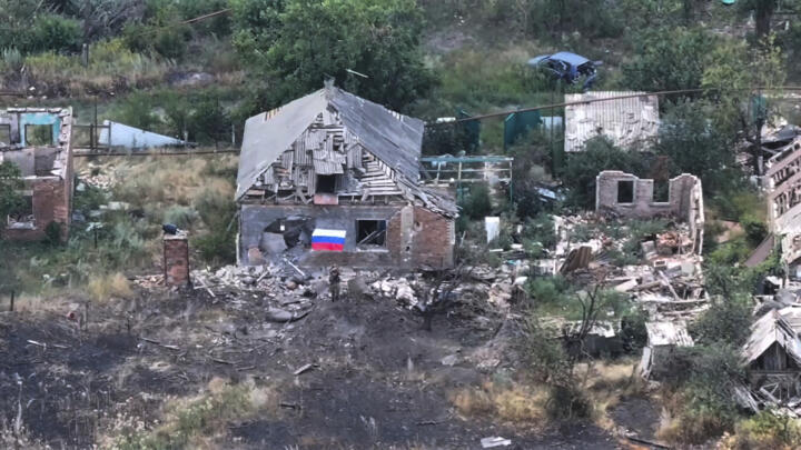 A Russian soldier waves a Russian flag among ruined buildings in the city of Chasiv Yar, in Donetsk, eastern Ukraine.