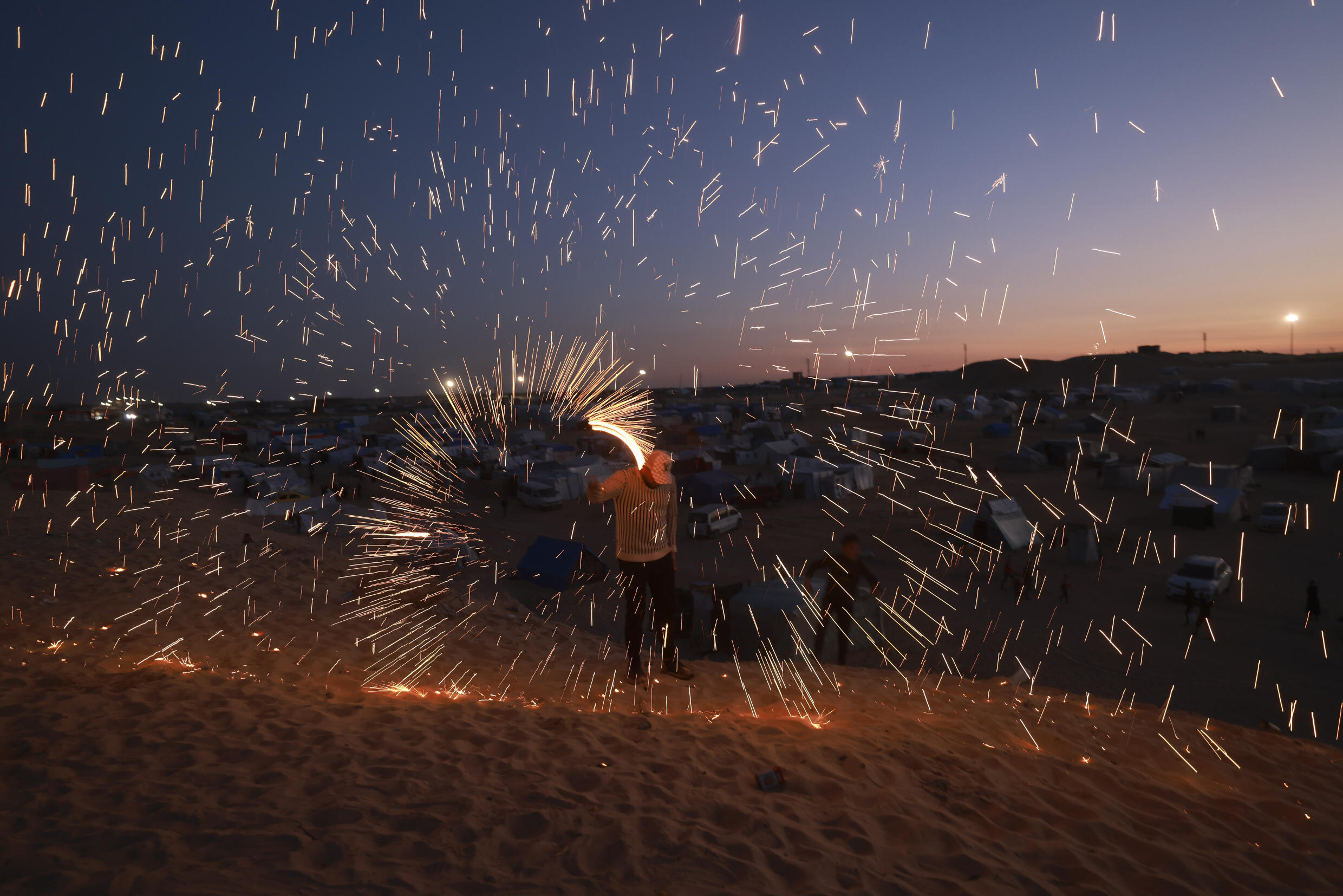 Un jeune Palestinien joue avec un feu d'artifice dans un camp de déplacés à Rafah, dans le sud de la bande de Gaza, à la veille du mois sacré de ramadan, le 10 mars 2024
