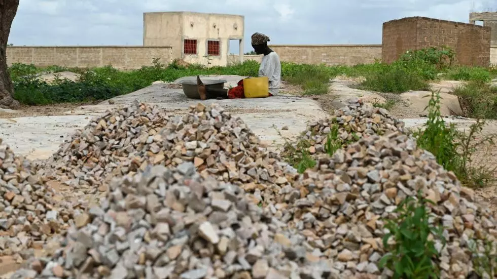 A woman, who is among the 300,000 internally displaced because of jihadist violence in northern and eastern Burkina Faso, sits on the ground between stones on September 17, 2019 in the village of Yagma near Ouagadougou.