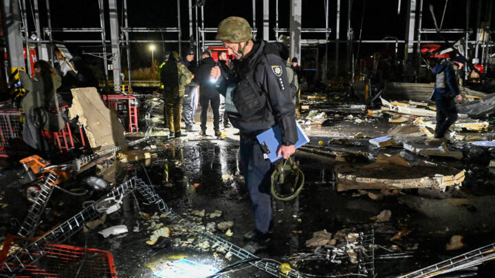 Police officers inspect the damage at a mail depot building following missile strikes at the village of Korotych in the Kharkiv region on October 21, 2023.