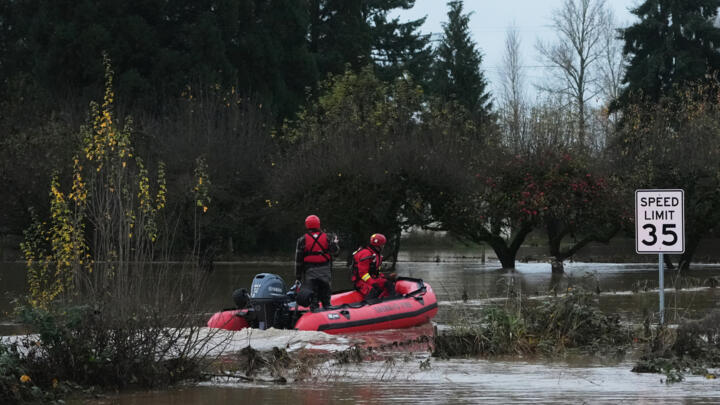 Rescue workers venture into a flooded neighborhood to pick up evacuees after heavy rains, December 9, 2025, in Washington, US.