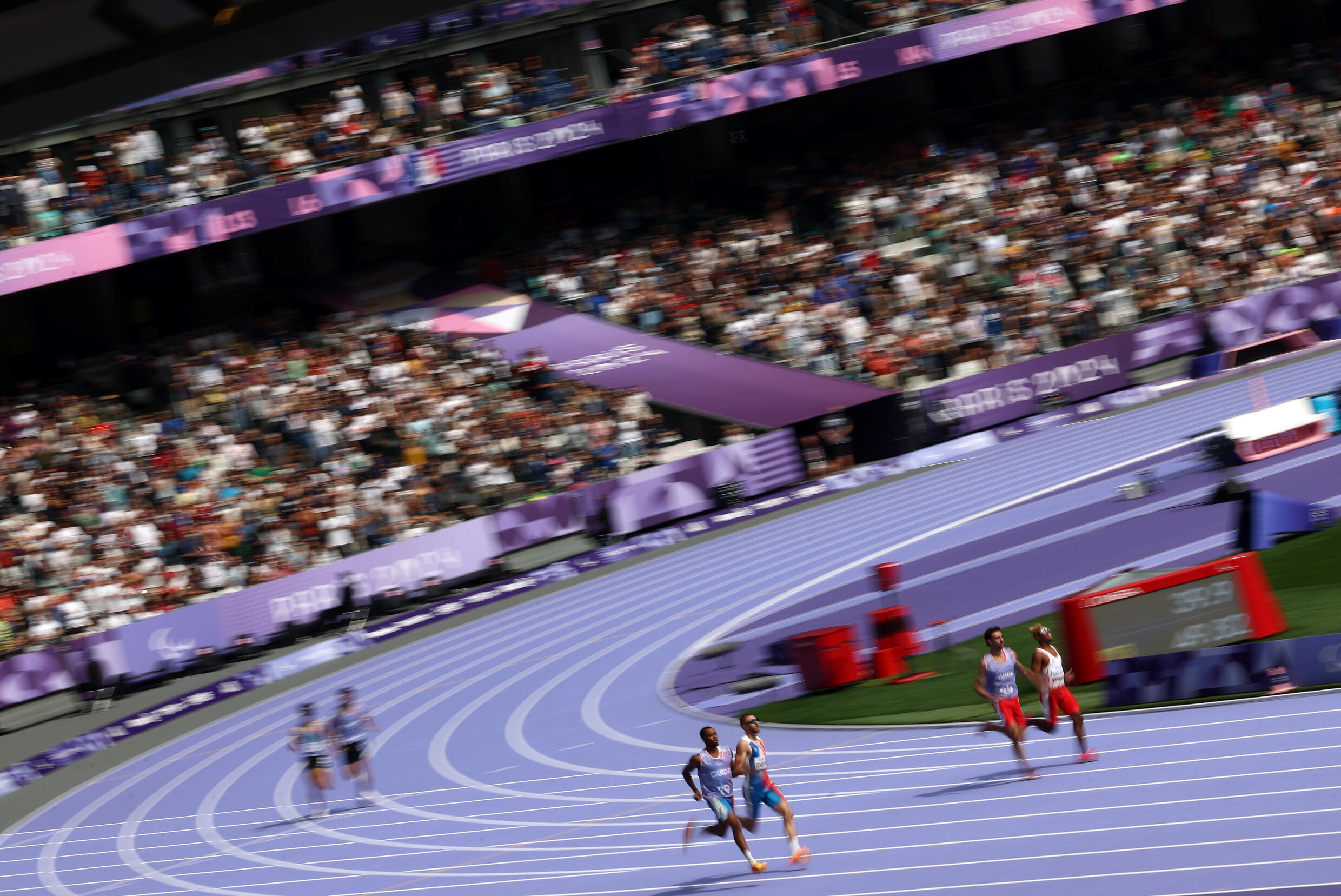Le Français Timothée Adolphe (au centre) lors des qualifications pour la finale du 400 m hommes T11 le 1er septembre 2024 au Stade de France près de Paris