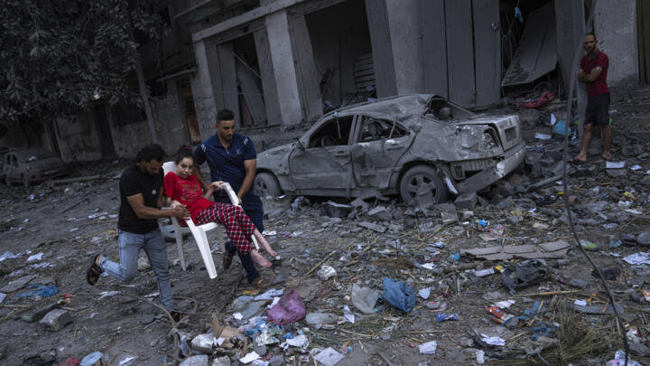 Palestinians walk among rubble after Israeli airstrikes razed large parts of a neighbourhood in Gaza City on October 10, 2023.