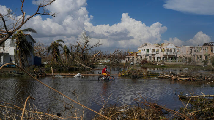 A man rides his bicycle through an inundated street in Black River, Jamaica, Thursday, October 30, 2025, in the aftermath of Hurricane Melissa.