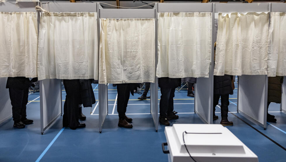 Des électeurs dans les isoloirs d'un bureau de vote à Nuuk, lors des législatives au Groenland, le 11 mars 2025.