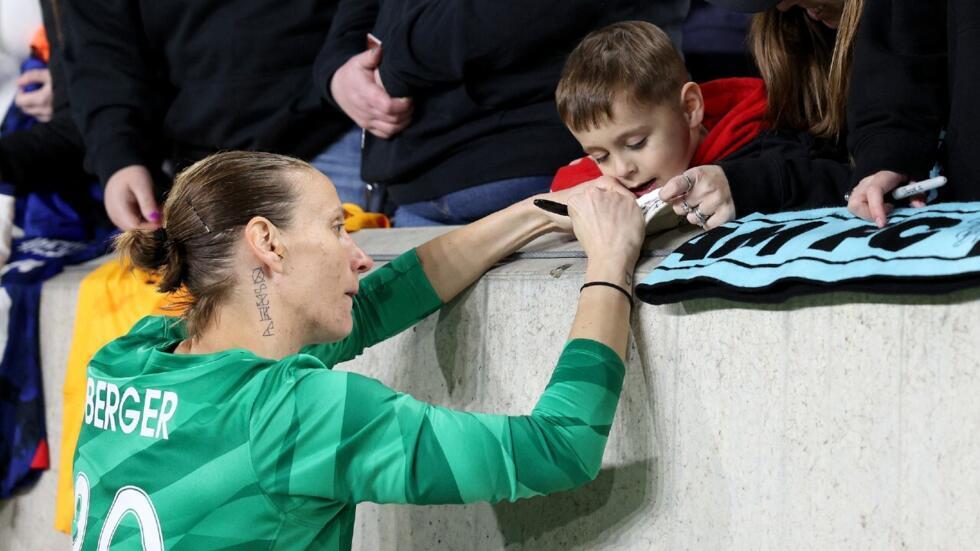 Le tatouage de d'Ann-Katrin Berger est visible sur ce cliché où elle signe un autographe à un jeune supporter du Gotham FC, à Harrison, dans le New Jersey, le 4 mai 2024.