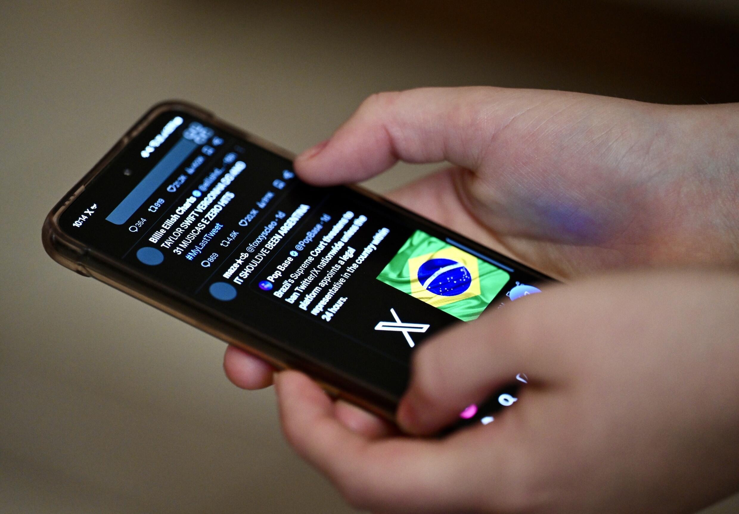 Un utilisateur du réseau social X, anciennement Twitter, consulte des messages sur un téléphone portable à Brasilia, le 31 août 2024 au Brésil