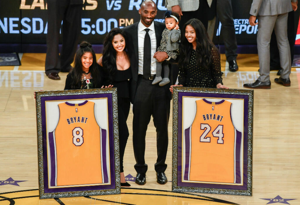 Kobe Bryant pose en famille sur le parquet des Lakers, avec ses deux maillots, le numéro 8 porté jusqu'en 2006, avant d'adopter le 24 pour la suite de sa carrière.