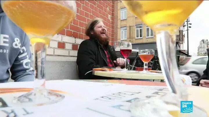A man laughs over beer with friends on a newly reopened Brussels terrace after a long wait due to the Covid-19 pandemic.